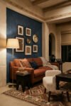 Rust sofa against a deep blue accent wall with framed art, brass floor lamp, patterned rug, and carved wood tables in a warm Nubian Style living room.