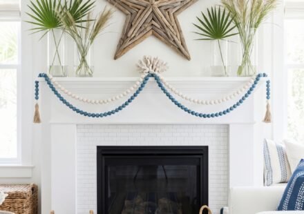 Coastal fireplace mantel with a driftwood star, blue and white bead garland, palm leaves, coral accent, and striped rug for breezy summer mantle décor inspiration.