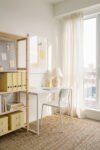 Summer Office Decor That Feels Light, Bright, and Lived In Sunlit white desk with yellow storage boxes, lemon wall art, sheer curtains, and woven rug creating a fresh Summer Office Decor look for a small apartment workspace.