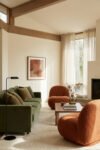 Green Burnt Orange Living Room Ideas With Rich, Easy Style Olive green sofa with burnt orange boucle chairs, wood coffee table, beige rug, tall sheer curtains and fireplace in a warm Green Burnt Orange Living Room