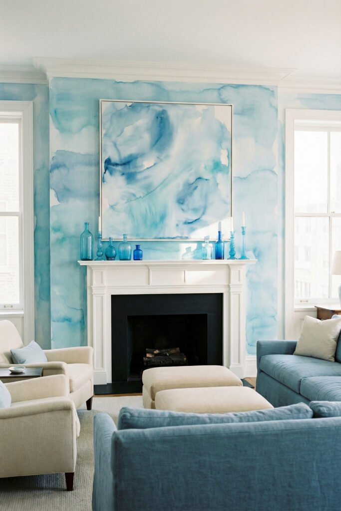 White fireplace framed by blue watercolor walls, oversized blue art, and blue glass bottles for bold artistic summer mantle décor.
