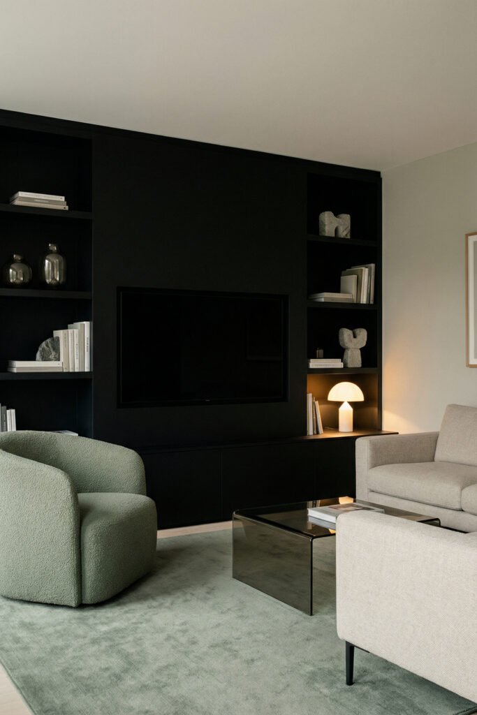 Sage Green And Black Living Room Ideas for a Layered Look 11 Black built-in TV wall with sage boucle chair, cream seating, smoked glass coffee table, and warm lamp creating a sleek layered living room.