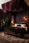 16 Cozy Bedroom Ideas for Couples to Create a Warm Shared Retreat Dark wood bed under sweeping burgundy canopy drapery, with cream bedding, wine accents, antique-style mirror, amber lights, and Persian-style rug.