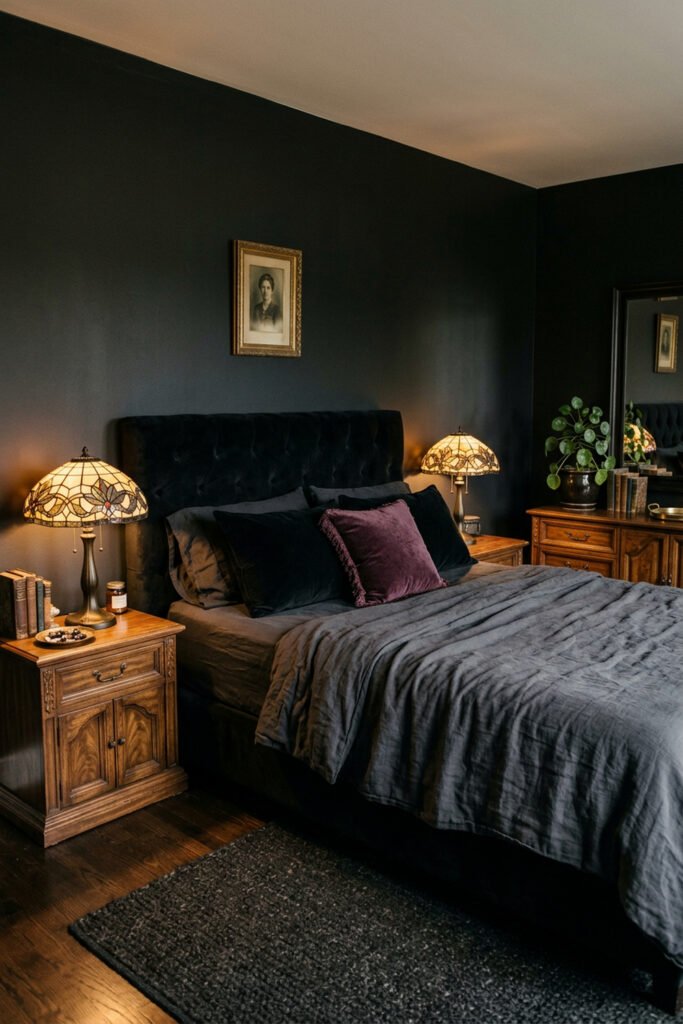 22 Black Nouveau Decor Ideas That Feel Dark, Rich, and Artful 11 Black upholstered bed with charcoal bedding, walnut furniture, matching stained-glass lamps, plum cushion, and dark walls.